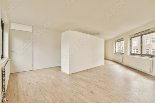 an empty living room with wood flooring and white walls  there is a large window to the left side