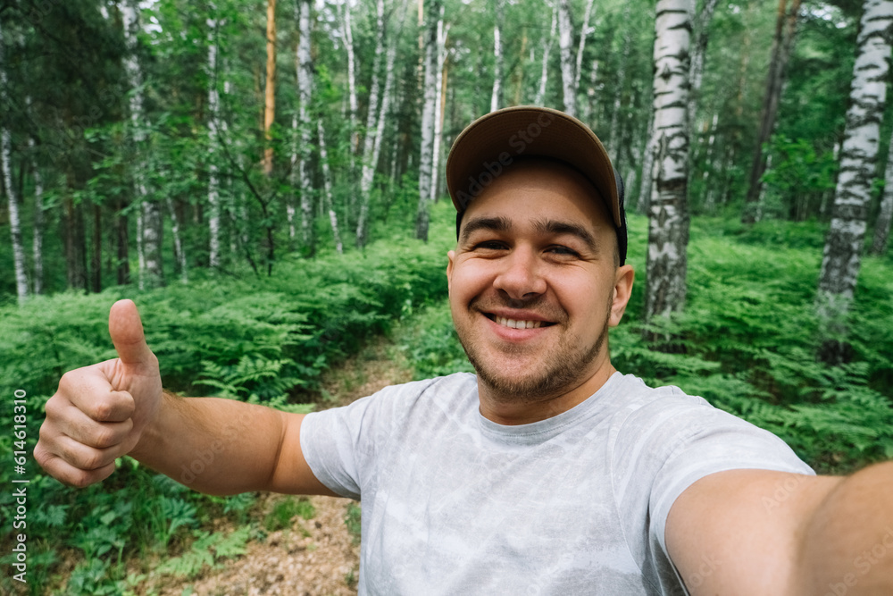 Naklejka premium Man smiling and taking a selfie in the forest