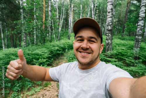 Man smiling and taking a selfie in the forest
