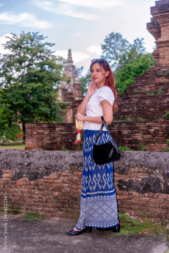 Young Asian women dressed in traditional costumes visit an old temple ...