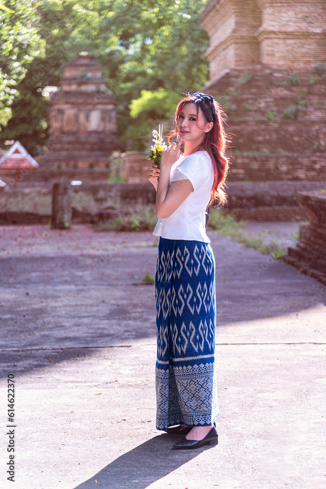 Young Asian women dressed in traditional costumes visit an old temple ...