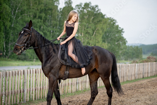Cute girl with long hair riding a horse outdoors, a beautiful frame with a horse © Irina