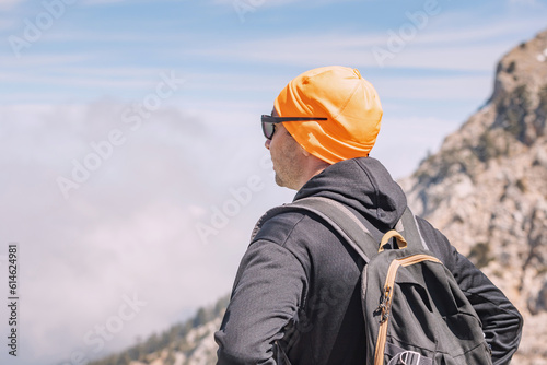 a male hiker or climber admires the view of the snow-capped spring mountains on the Lycian way
