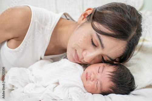 happy loving family. mother playing with her baby hugging in the bedroom , portrait of asian mother playing with newborn baby, health care family love together. asian girl lifestyle..