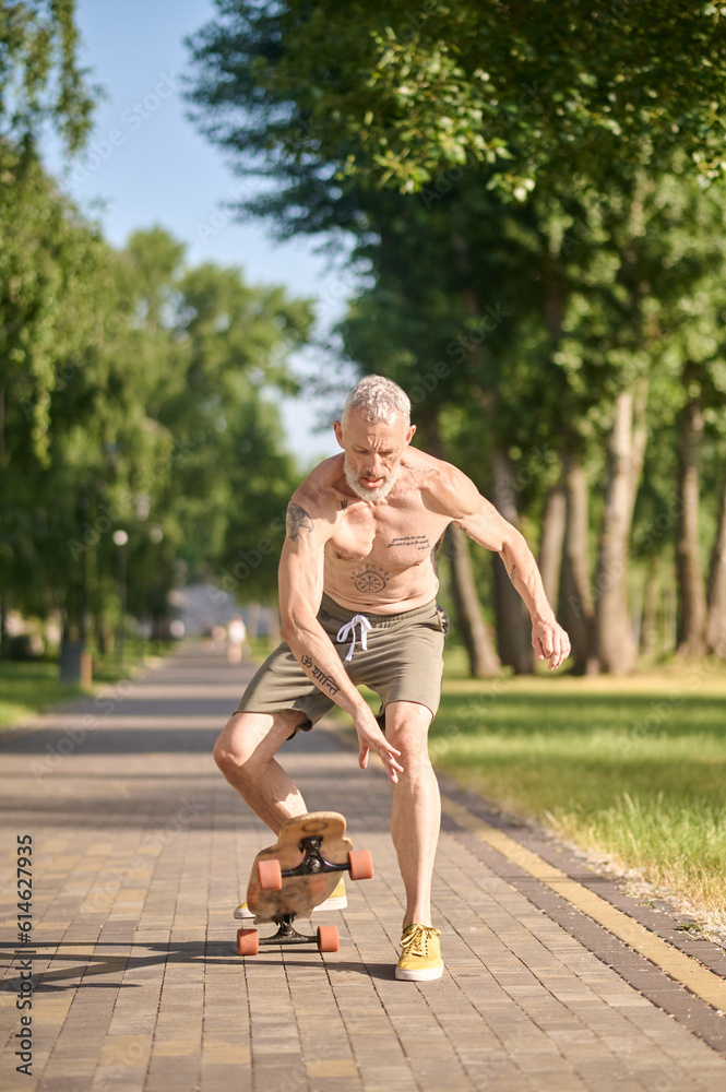 Obraz premium Sportive man with riding longboard in a city park