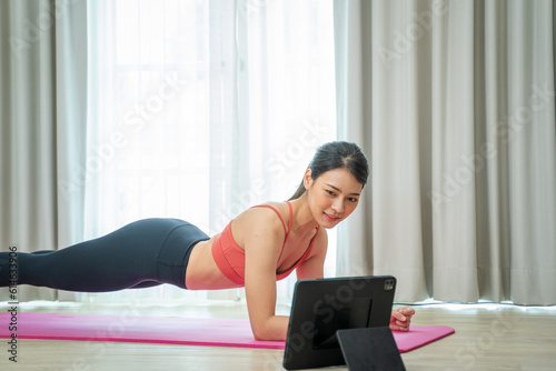 Young woman using tablet pc doing yoga stretching yoga online at home,Entertainment and education on the Internet.