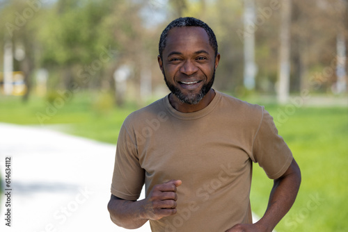 Mature african american man jogging in the park and looking contented