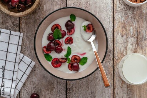 yogurt with cherries in a plate, milk in a bottle and glass on a