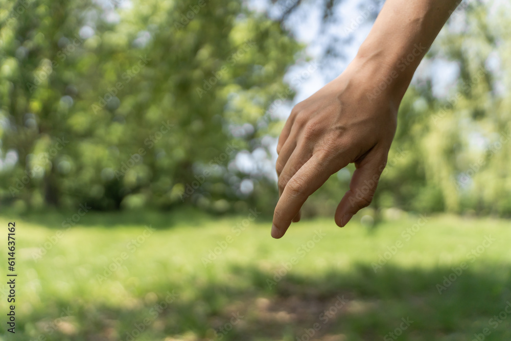 Helping woman's hand on green nature background. Female hand of support with copy space. Concept of help, mental health.