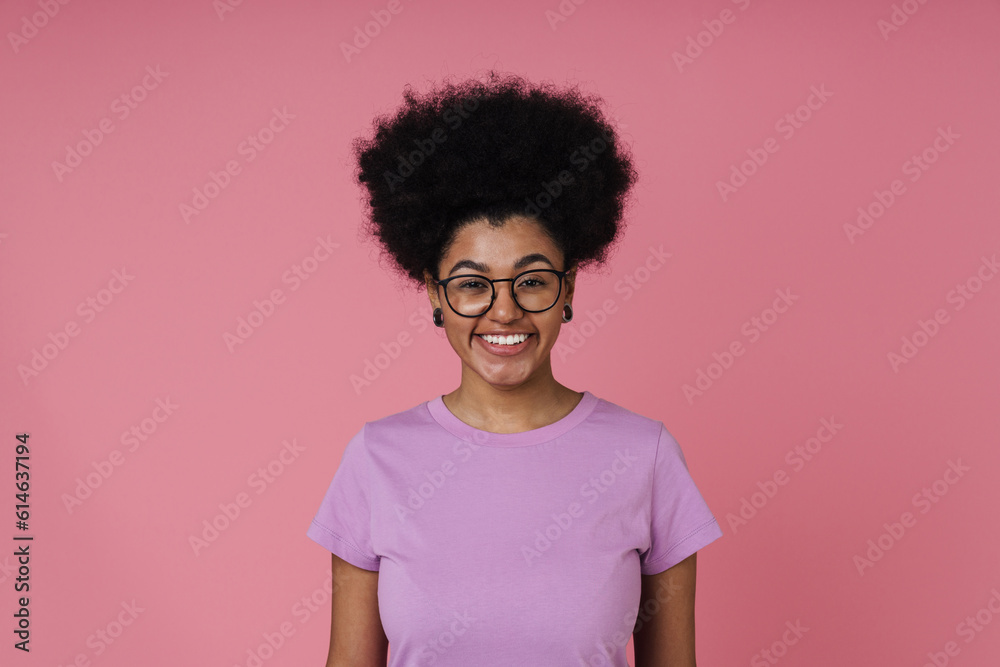 Cheerful afro woman smiling at camera while standing isolated over pink wall Cheerful afro woman smiling at camera while standing isolated over pink wall