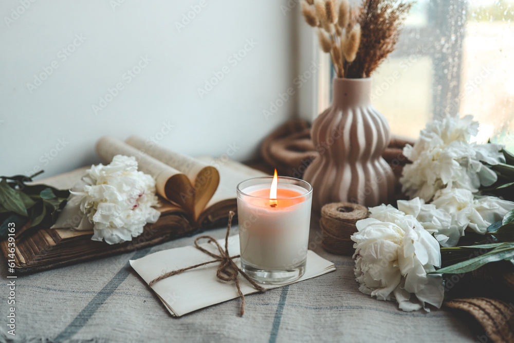 Burning candle and white peonies, vintage aesthetic