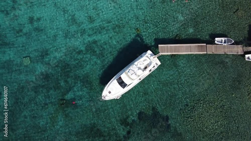 Ferretti Speedboat Yacht moored to Mooring Buoy at wooden Jetty dock in Blue Lagoon of Veliki Budikovac, Croatia. Aerial photo