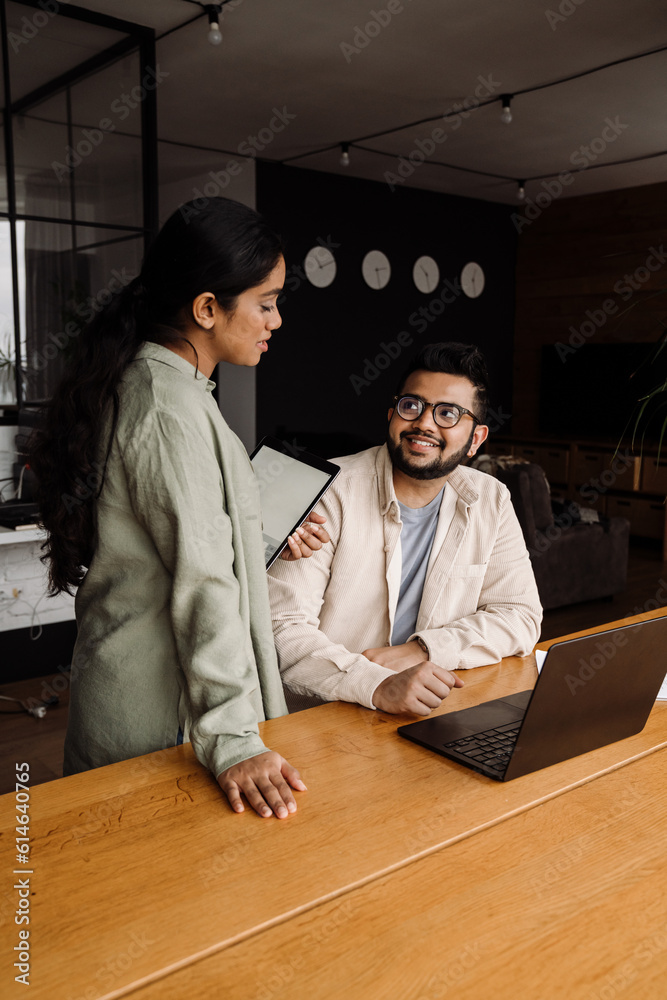 © Drobot Dean - Two indian colleagues using laptop and tablet while working together in office