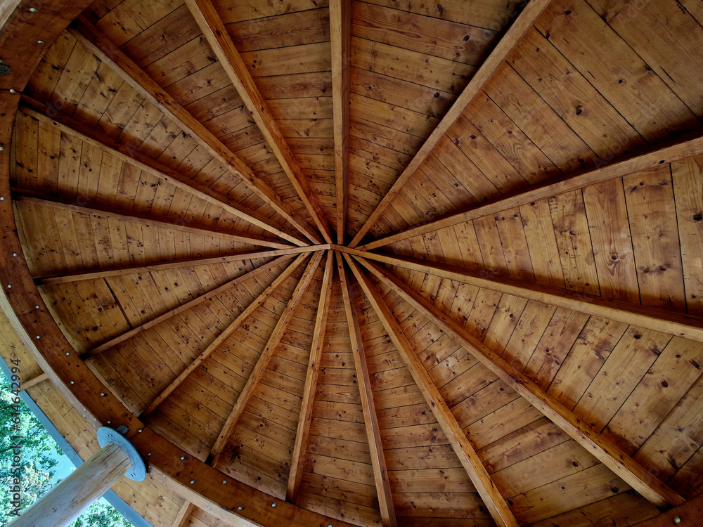 pergola ceiling made of wooden beams by carpentry by grafting wood into the shape of an octagon. at the top are windows like a lighthouse. oval, elipse