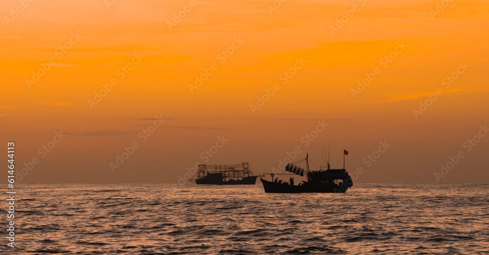 Seascape at dawn with silhouettes of Vietnamese fishermen's fishing boats with yellow-orange light background of Binh Minh. Sea landscape concept and sea work.