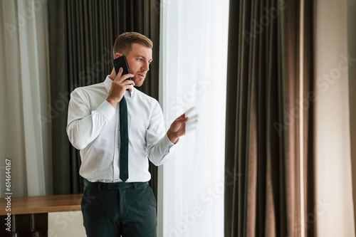 Business call, talking by phone. Man is indoors in the hotel room