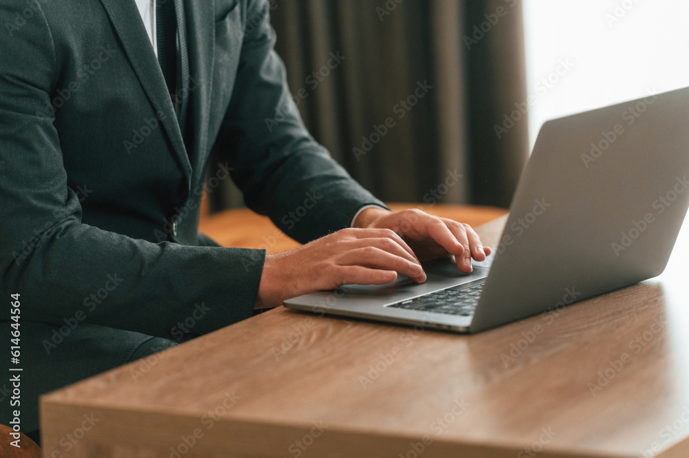 Close up view of businessman in suit and tie that is working by using laptop Close up view of businessman in suit and tie that is working by using laptop