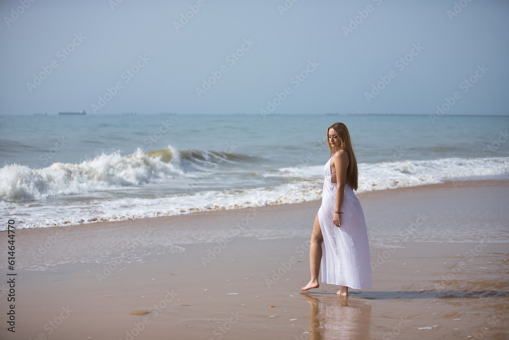 Young, beautiful, blonde woman in white dress, posing on a lonely beach, relaxed and calm. Concept peace, tranquility, solitude, tenderness, virginity. Young, beautiful, blonde woman in white dress, posing on a lonely beach, relaxed and calm. Concept peace, tranquility, solitude, tenderness, virginity.