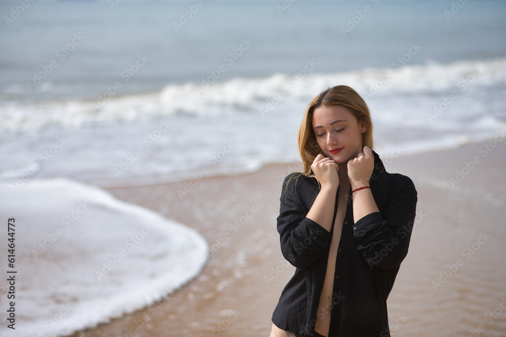 Young woman, blonde and beautiful, wearing a bikini and black shirt, clutching the collar of the shirt, loving herself. Concept purity, virginity, protection. Young woman, blonde and beautiful, wearing a bikini and black shirt, clutching the collar of the shirt, loving herself. Concept purity, virginity, protection.