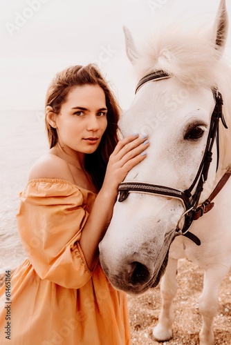 A woman in a dress stands next to a white horse on a beach, with the blue sky and sea in the background.