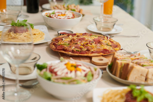 Delicious homemade pizza, sandwiches and spaghetti on dinner table