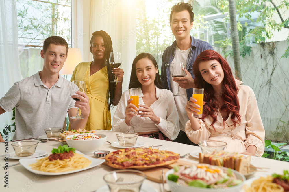 Group of happy friends toasting with glasses of wine and fruit juice