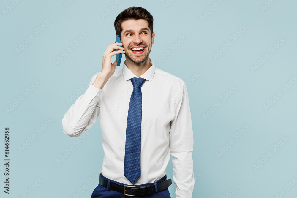 Young successful employee business man corporate lawyer wear classic formal shirt tie work in office hold in hand use mobile cell phone isolated on plain pastel light blue background studio portrait. Young successful employee business man corporate lawyer wear classic formal shirt tie work in office hold in hand use mobile cell phone isolated on plain pastel light blue background studio portrait.