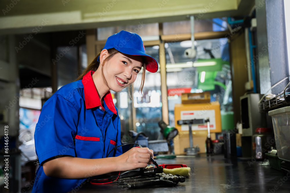A female diesel engine mechanic in a blue uniform is working at the garage. Inspect and maintain the fuel pressure booster pump system and common rail injectors. A female diesel engine mechanic in a blue uniform is working at the garage. Inspect and maintain the fuel pressure booster pump system and common rail injectors.