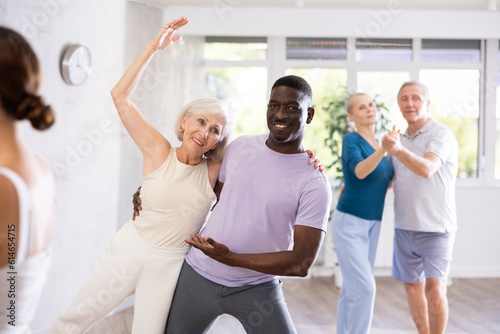African-American man dances steamy salsa with elderly female companion for fitness classes and enjoys movement and activity. Hobbies, active pastime