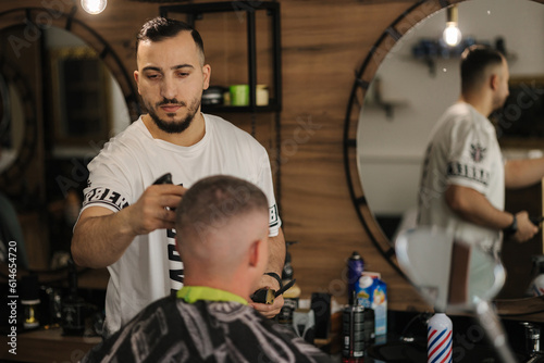 Handsome man on a haircut in the barber sits on a chair.