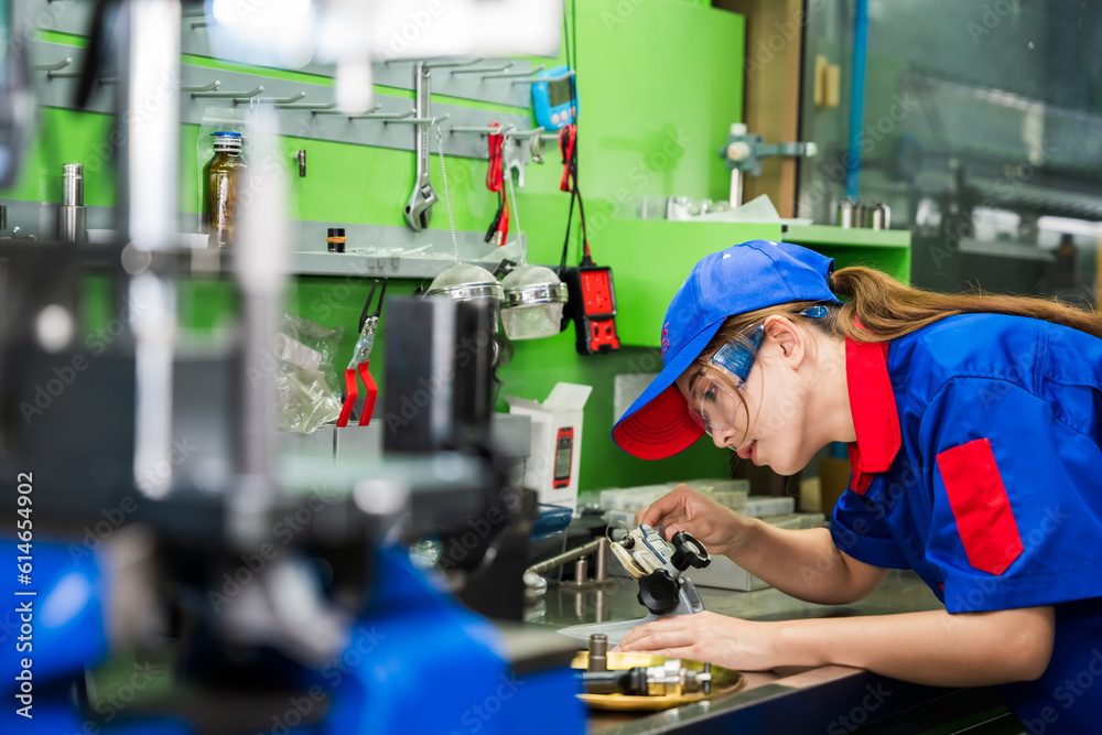 © SKW - A female diesel engine mechanic in a blue uniform is working at the garage. Inspect and maintain the fuel pressure booster pump system and common rail injectors.
