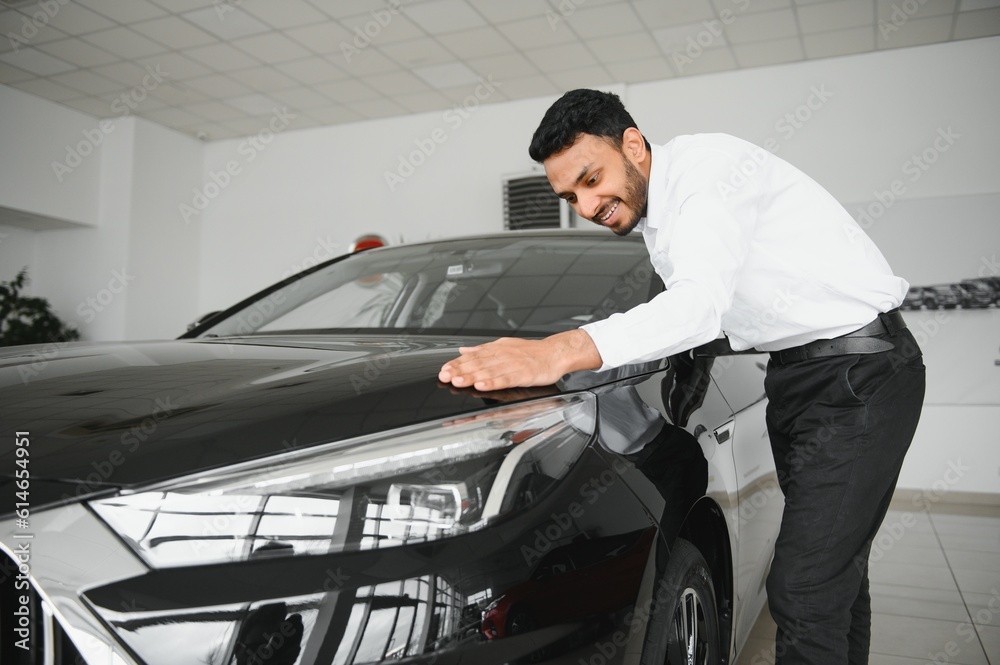 A young Indian man chooses a new car at a car dealership