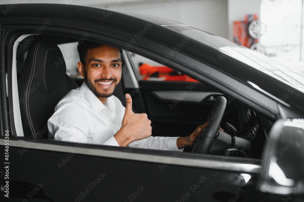 Young man sitting inside new car. Smiling