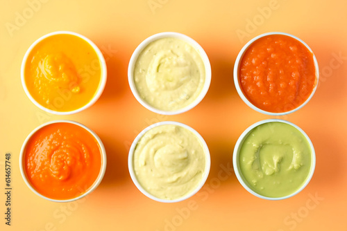 Bowls with healthy baby food on a colored background. Top of view. Generative AI