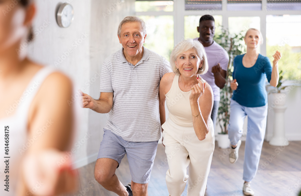 Fototapeta premium Cheerful elderly amateur couple visiting group choreography class, practicing vigorous lindy hop moves. Concept of active lifestyle