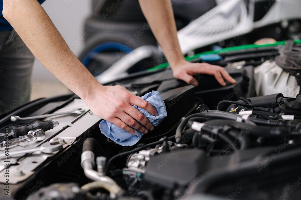 Auto mechanic working in garage man wipes the car engine. Process of repair car on service. Auto mechanic working in garage man wipes the car engine. Process of repair car on service.