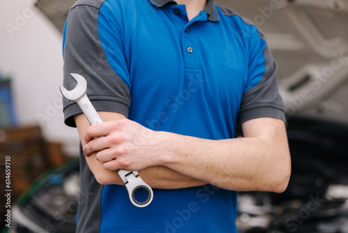 Middle selection of male mechanic hold auto repair tool. Man stand in front of car with open hood