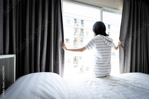 Slika na platnu Asian young woman opening curtain and window for hygienic,sunlight to enter her