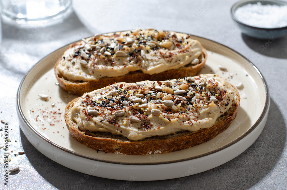 Hummus Toast with Rustic Bread, Vegetarian Snack or Breakfast on Bright Background Hummus Toast with Rustic Bread, Vegetarian Snack or Breakfast on Bright Background