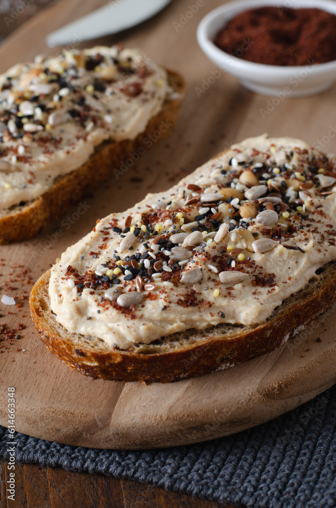 Hummus Toast with Rustic Bread, Vegetarian Snack or Breakfast on Wooden Background Hummus Toast with Rustic Bread, Vegetarian Snack or Breakfast on Wooden Background