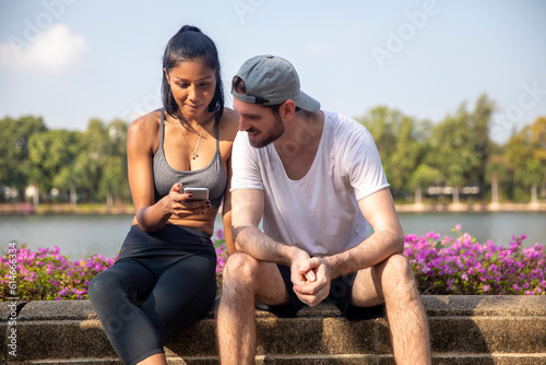 Man looking at smart phone held by woman sitting on bench