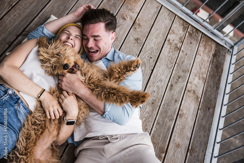 Happy young couple enjoying with dog on balcony photo