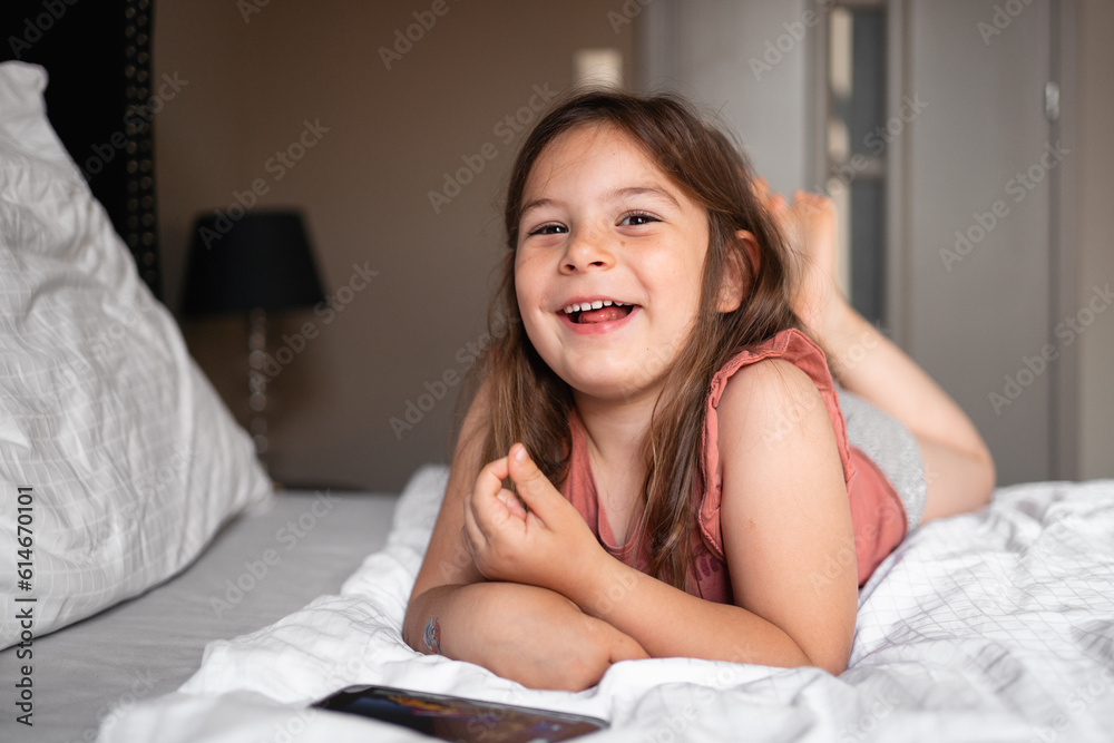 5 years old girl watching cartoons on mobile phone on the bed. royal luxury interior 5 years old girl watching cartoons on mobile phone on the bed. royal luxury interior