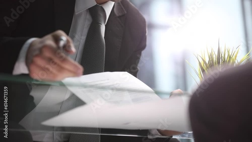 Businessman leafing through documents and signing contract for business deal at work in office closeup