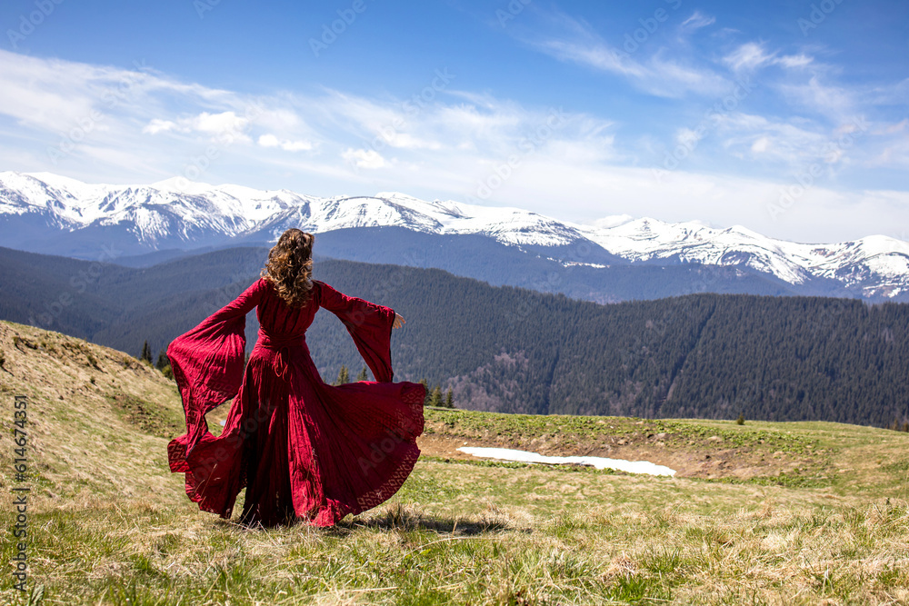 Woman dancing in the mountains. A beautiful view of the mountains. Red dress