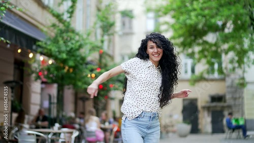 Happy young woman dancing on the city street. Cheerful Curly Attractive Pretty Female dancer Enjoying Life, Happiness Joy urban Lifestyle Concept. Beautiful Cute funny Girl look at camera outdoor