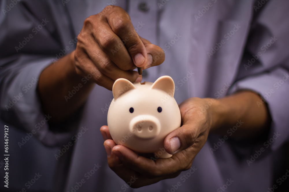 piggy bank on hand. Contents of Collecting Money and Investments. man hand puts coins into a piggy bank. piggy bank on hand. Contents of Collecting Money and Investments. man hand puts coins into a piggy bank.