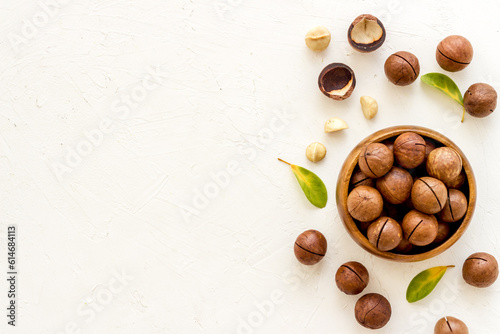 Shelled macadamia nuts with green leaves. Healthy snack background photo