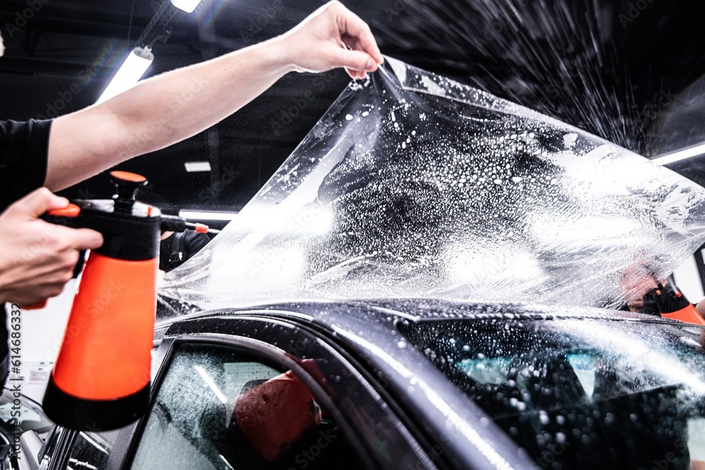 Application of self-healing PPF film on the car roof in a car detailing studio