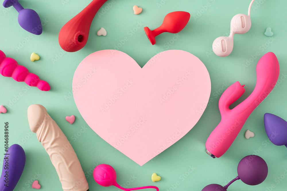 Erotic pleasure toy concepts for adults. Top view flat lay of colorful vibrators, dildo, anal plugs, vaginal balls, little hearts on turquoise background with blank heart for text or promo - obrazy, fototapety, plakaty 